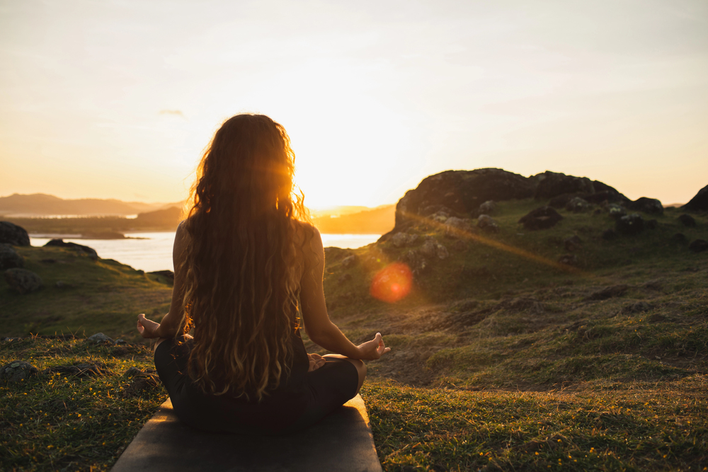 woman sitting on mountain meditating