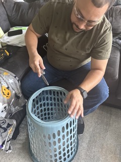 man cutting hole in laundry basket for halloween costume