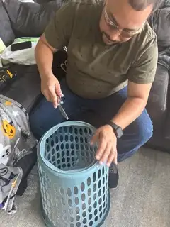 man cutting hole in laundry basket for halloween costume